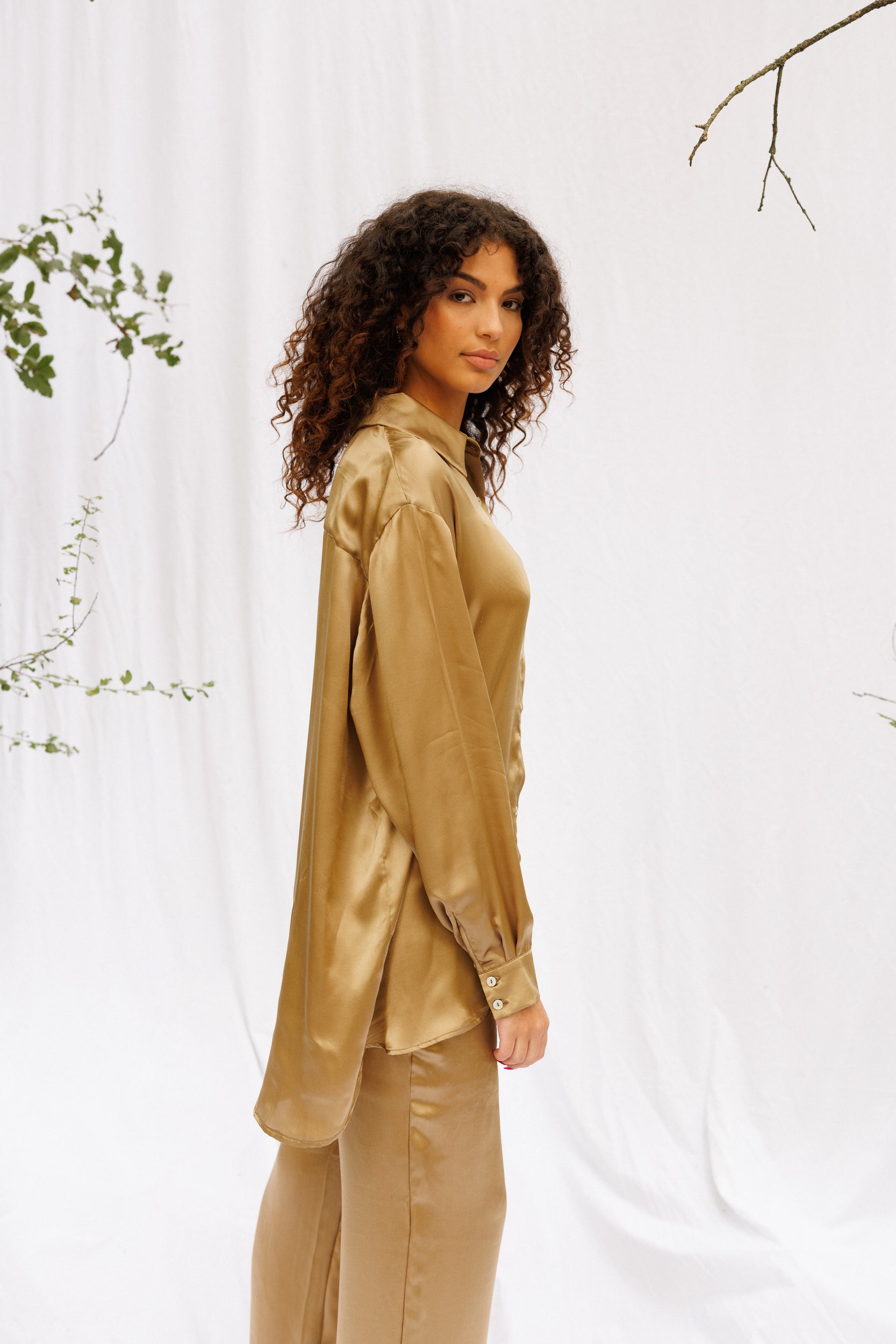 Closer image of Maria wearing oversized shirt and pants in brown gold