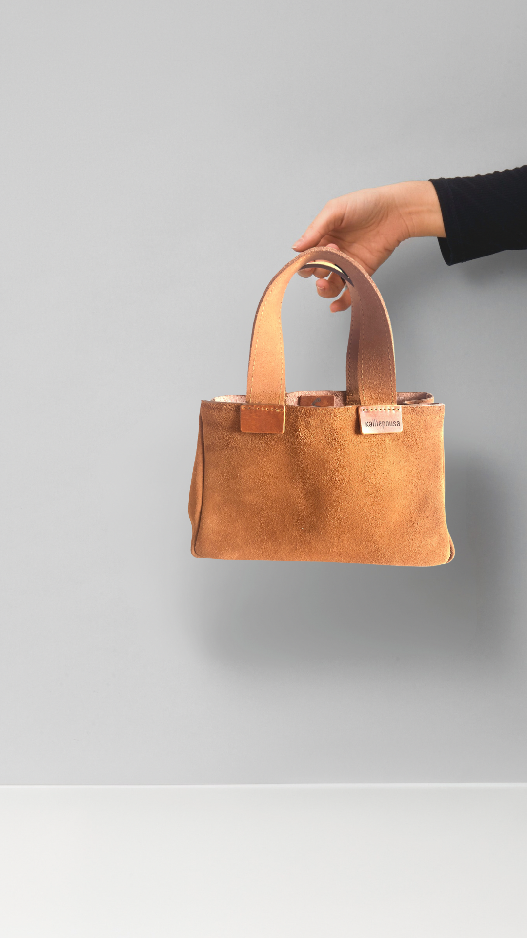 A hand that holds Brown leather bag 